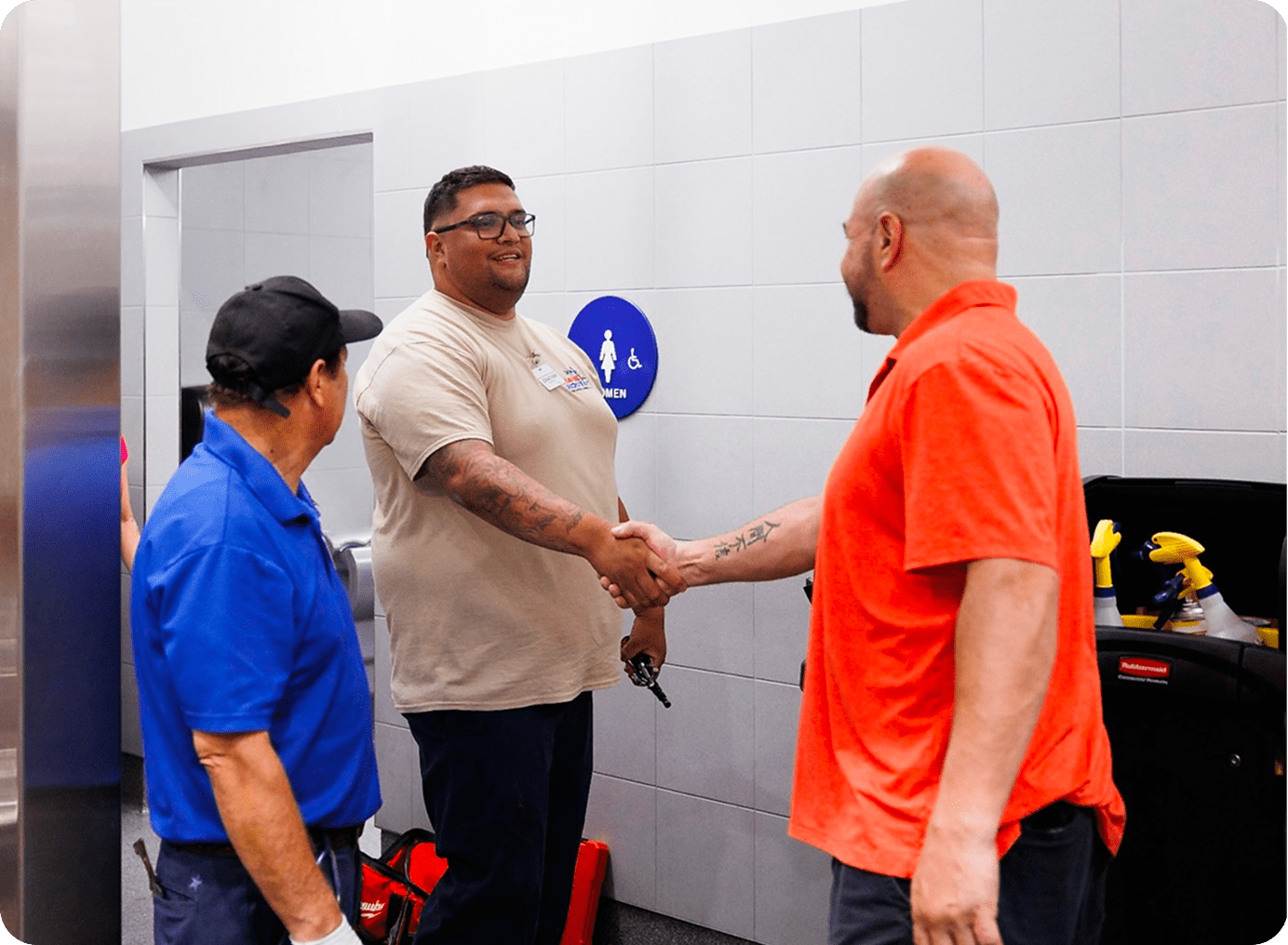 Three men shaking hands in a restroom.