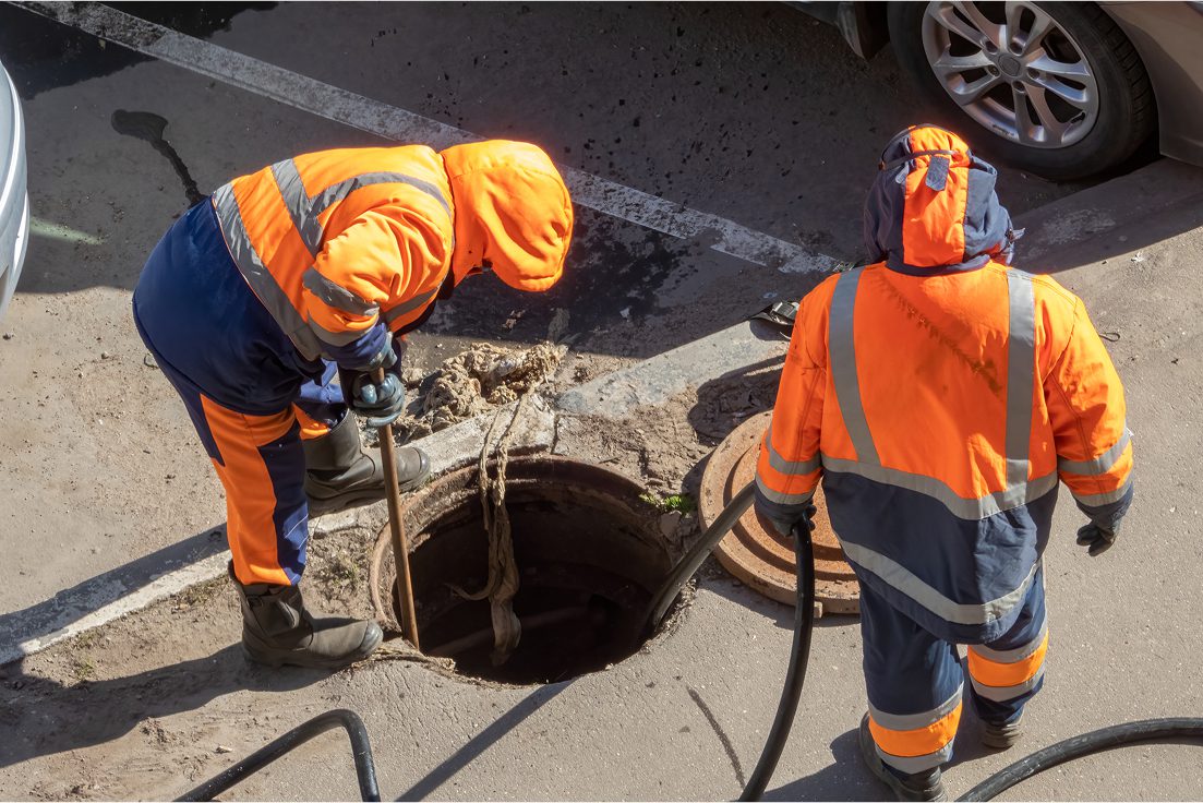 Workers cleaning a street manhole.