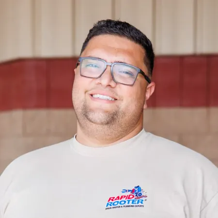 Smiling man wearing glasses and a logo shirt.