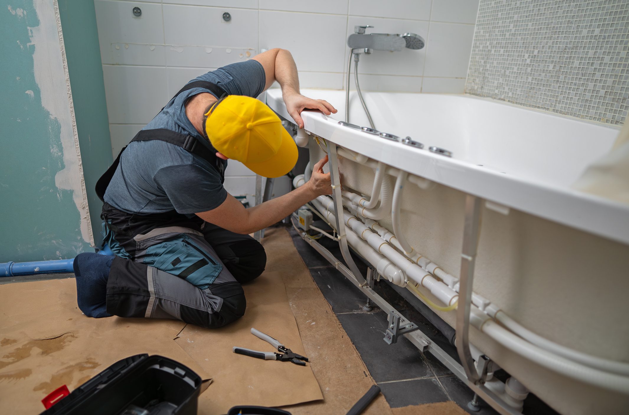 Man servicing the pipe system of a bathtub with hydromassage.